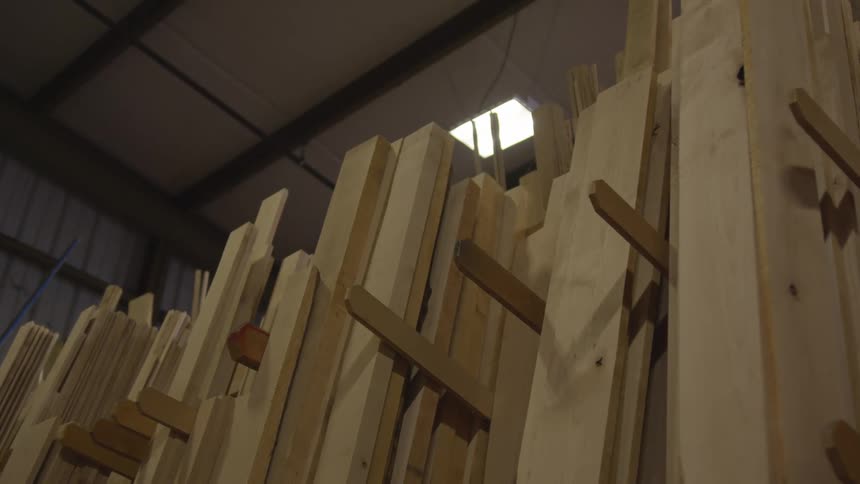 A slow camera pan reveals stacked wooden planks of various sizes on a shelf inside a lumber store
