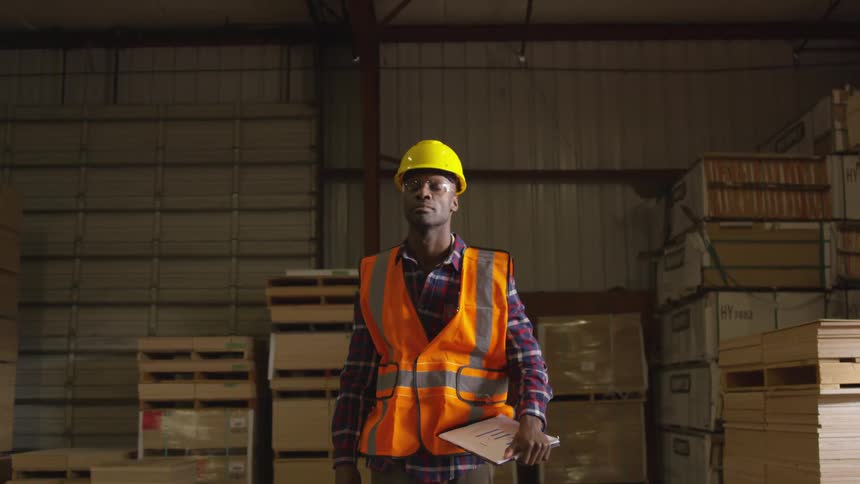 A man carries his clipboard through the lumber yard