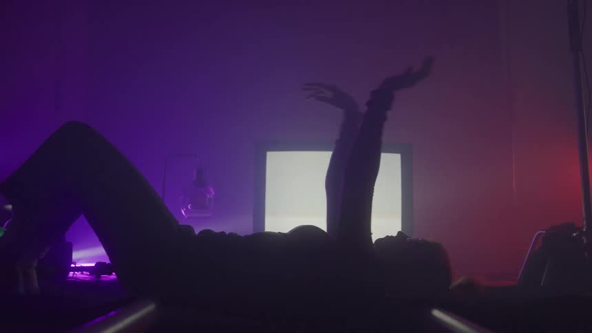 A woman waves her arms in front of the static filled television