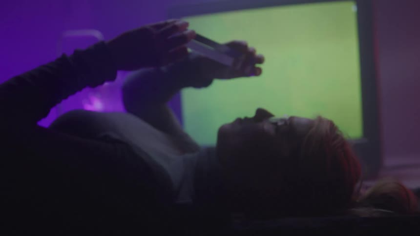 Woman examines a clear crystal while in a room lit by colored lighting