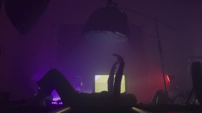 A woman waves her arms while laying in front of the television
