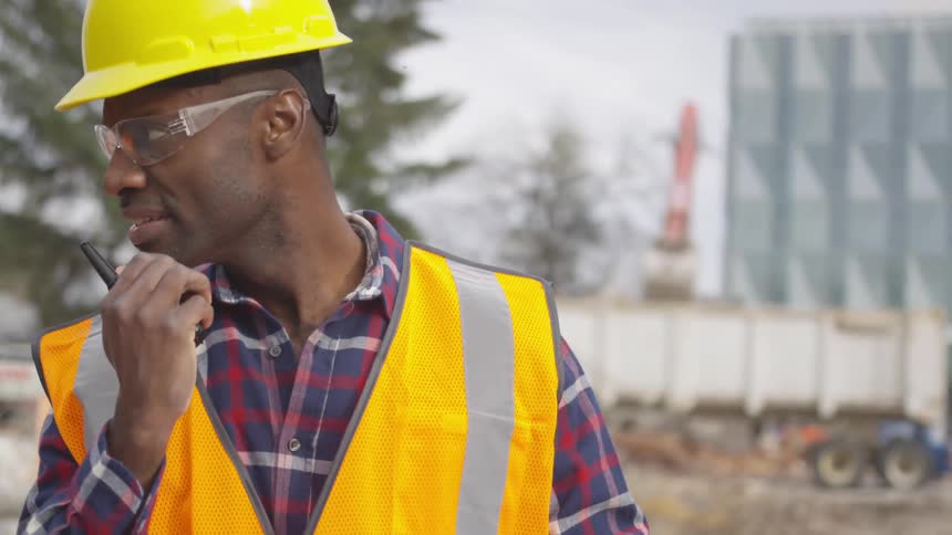 Man talks into a walkie talkie at a construction site