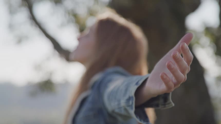 A woman is standing outside with her arms stretched out