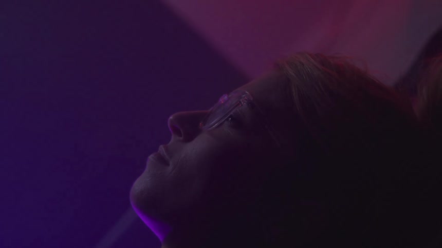 Woman wearing glasses is lying down and staring straight ahead