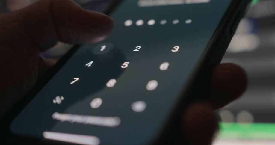 Person holding cell phone entering a password with thumb
