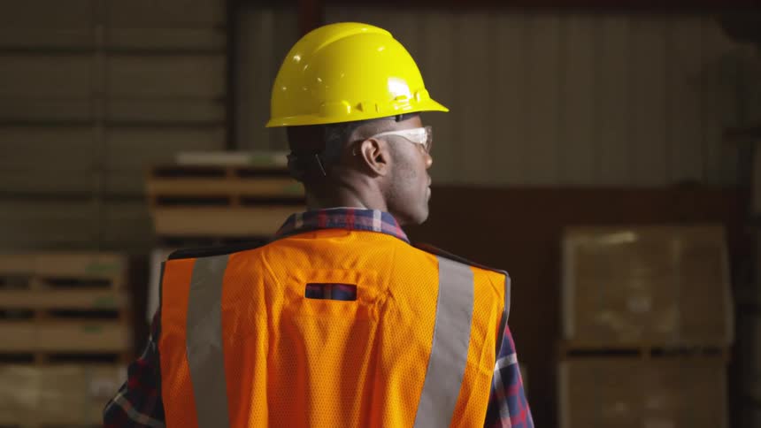 Man in a hardhat walking around and looking at a warehouse