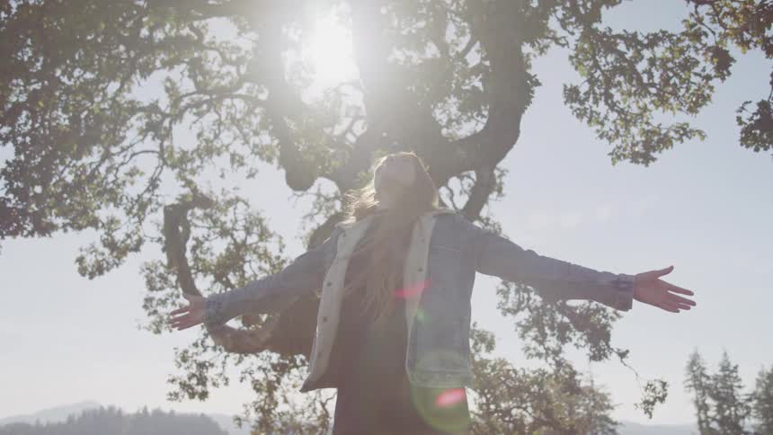 Girl jumping with open arms in the middle of nature