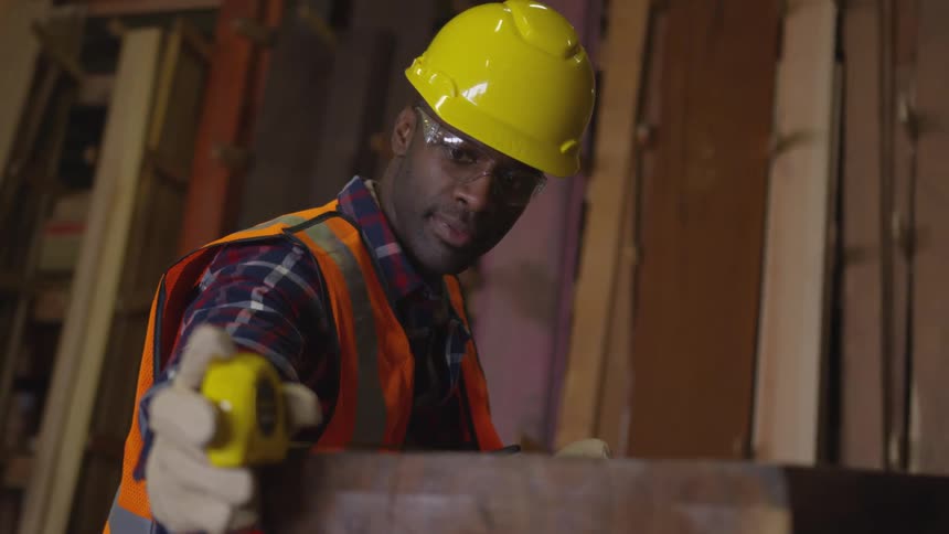 Worker who measures a piece of wood