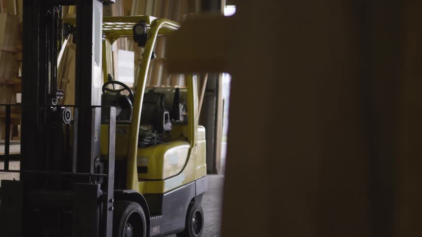 A forklift is parked inside a lumberyard