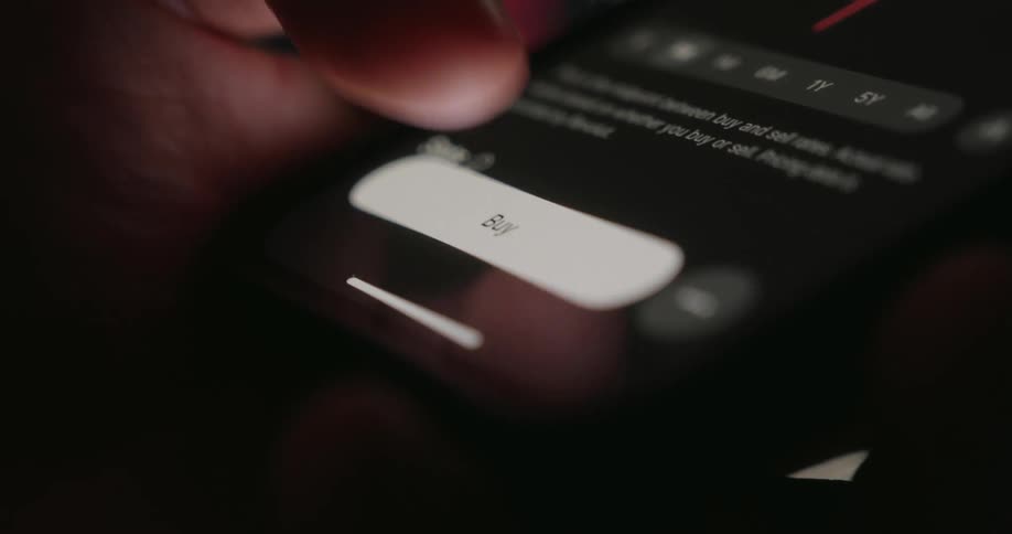A closeup shot shows a finger pressing the buy button on a crypto trading app triggering a screen transition