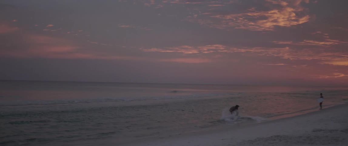 A man is surfing near the coast on the water at dawn