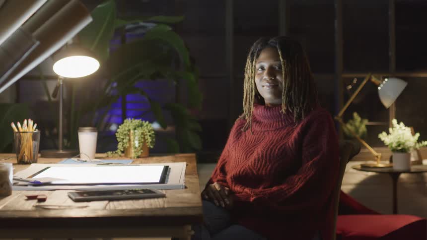 During the night time a woman is smiling at her desk