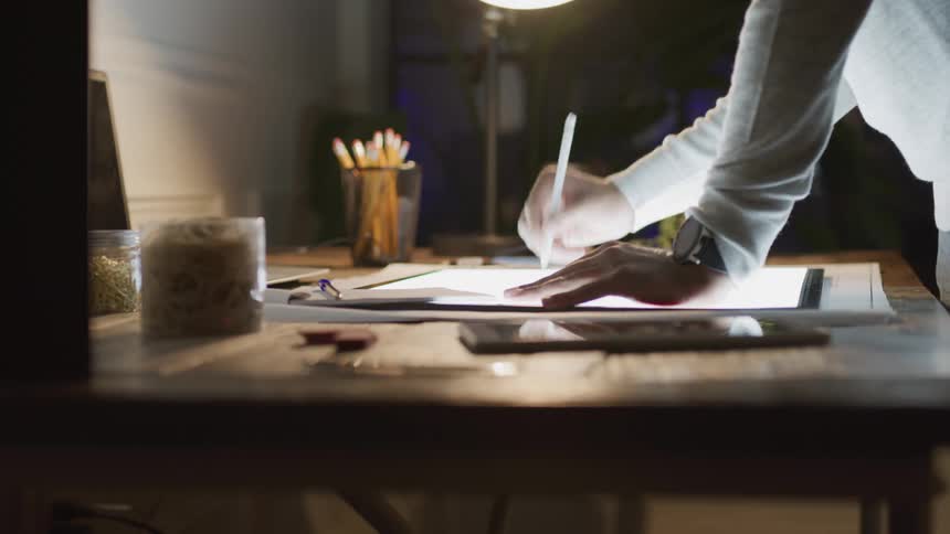 A man is drawing on a lit up sketch pad