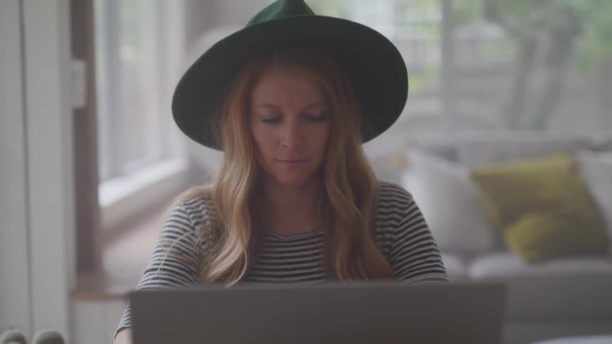 Teenage girl wearing a hat typing on a laptop computer
