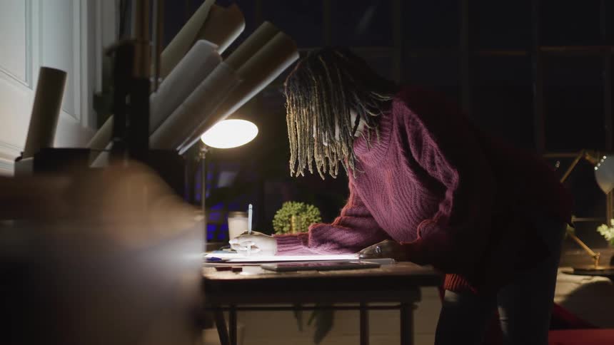 A woman leans over her desk writing