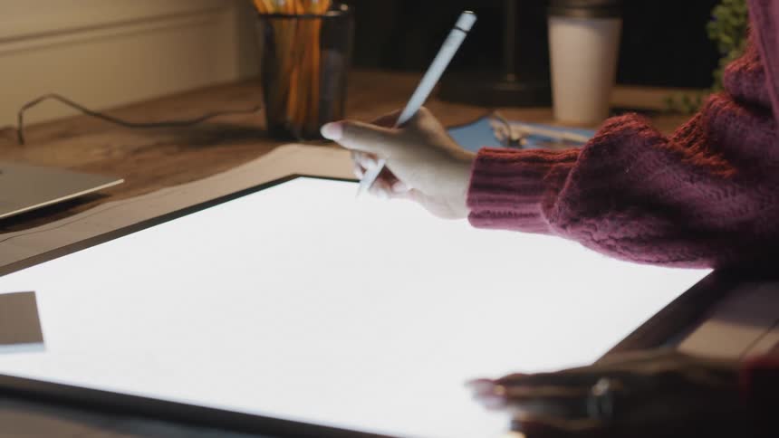 A person is using a stylus to write and draw on a large tablet the camera is still we only see their hands doing the work not what the work is