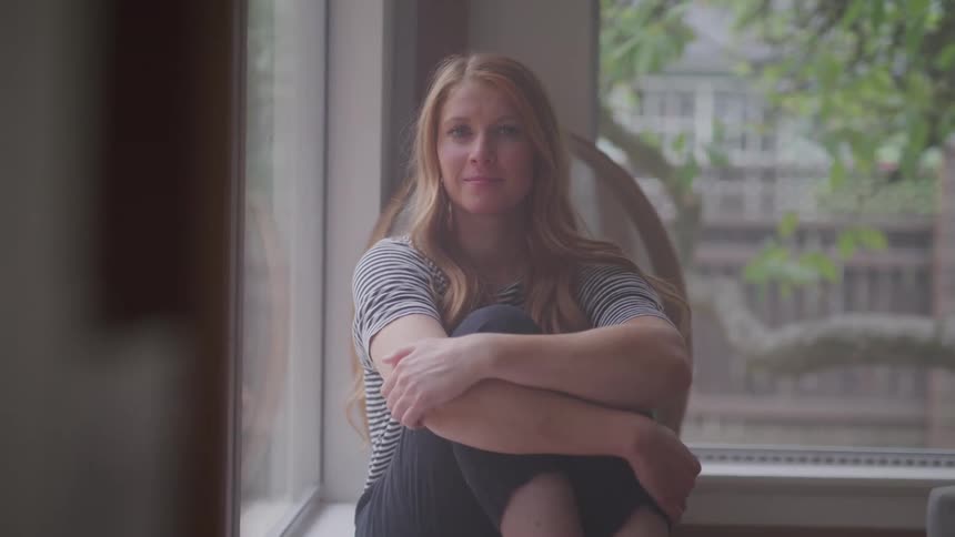 Girl sitting on a window with her legs gathered