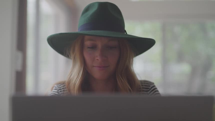 Girl in a hat typing on a computer