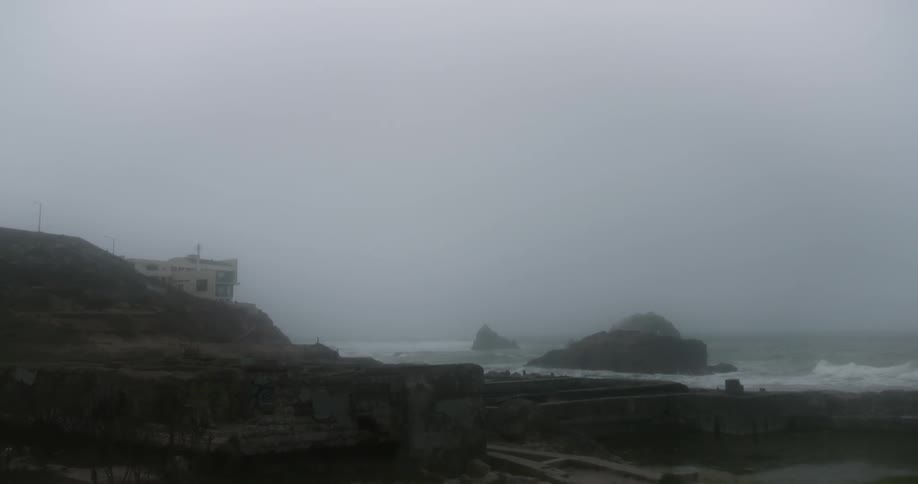 The waves crash against the shore on a foggy day