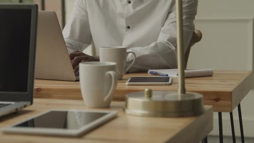 A man is typing on his laptop at the desk