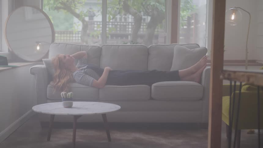 Woman touching her hair while completely outstretched on the sofa