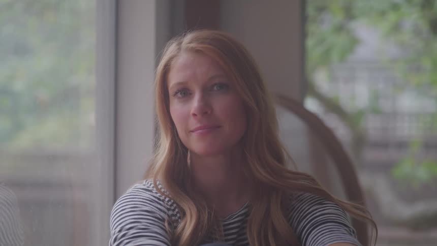 Woman sitting next to the window turns to face straight ahead
