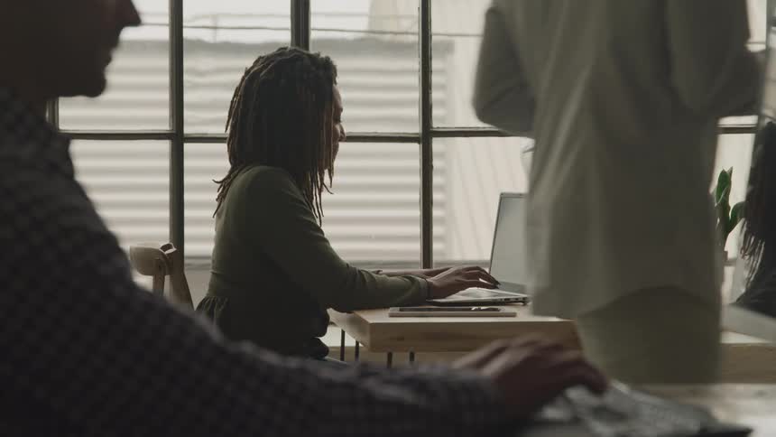 Workers are sitting at desks typing on laptops