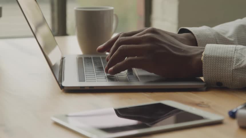 A person sitting at a desk and typing on their laptop