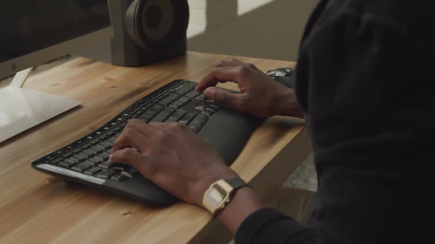 Man types on a computer keyboard at a desk
