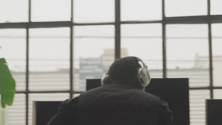 Man puts on headphones before sitting down in front of a computer on the desk