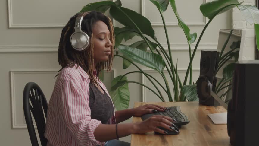 A woman listens to music and uses her computer mouse