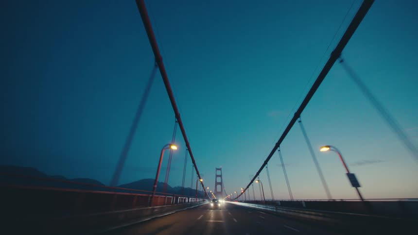 The sun is rising as traffic goes over the bridge