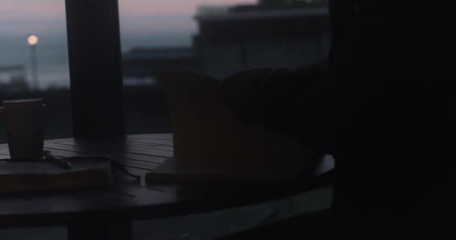 A man puts a book on a table at dawn and opens it
