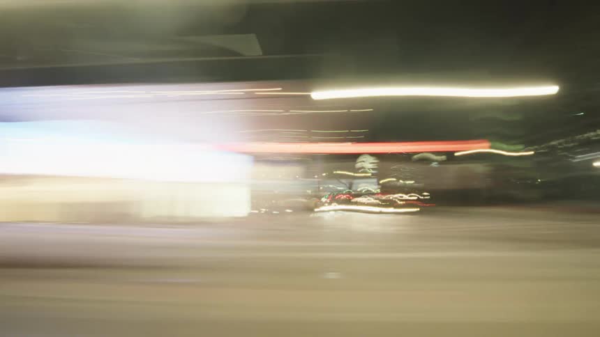 A chaotic timelapse blurs through a nighttime cityscape as colorful lights streak across the frame from traffic signals street lamps and passing vehicles