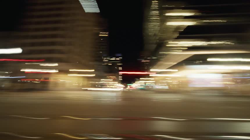A nighttime urban scene featuring motionblurred lights and buildings as seen from a fastmoving vehicle
