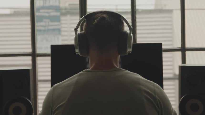 Man wearing headphones as he sits in front of a computer