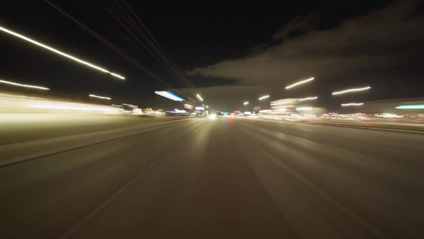 Lights from the buildings fly by on the road
