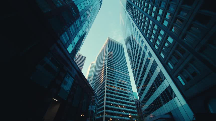 The towering height of skyscrapers in a city with the perspective emphasizing their vertical lines and the narrow strip of sky above