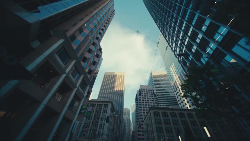A dramatic upward looking shot of towering skyscrapers against a cloudy sky