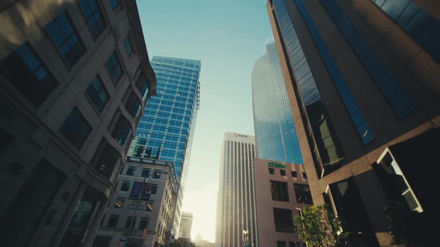 A cluster of buildings in a city against a clear sky with a tall light colored building in the center