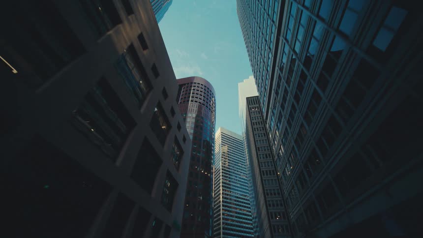 Tall buildings cast darkness between them under a bright sky