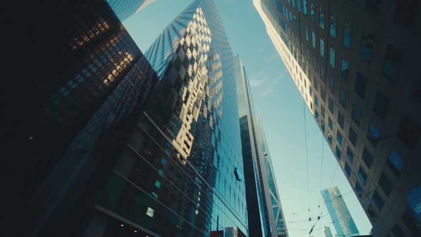 The towering skyscrapers of a modern city their glass facades reflecting the blue sky above