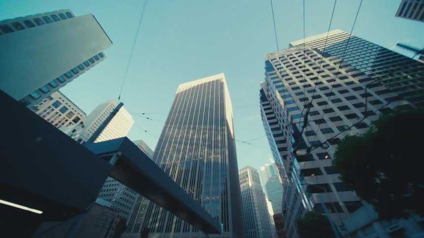 A cluster of tall buildings against a clear sky with overhead wires adding a dynamic element to the urban landscape