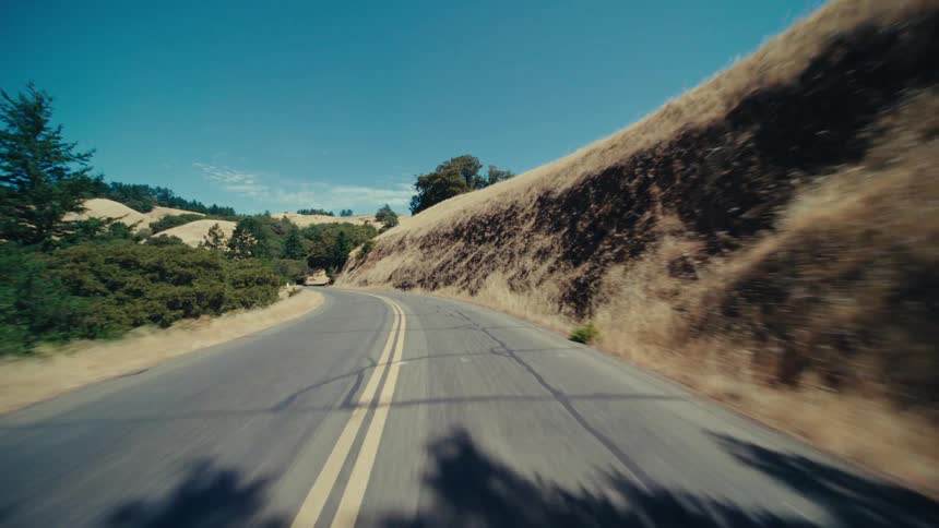 A road runs through a hillside under a blue sky