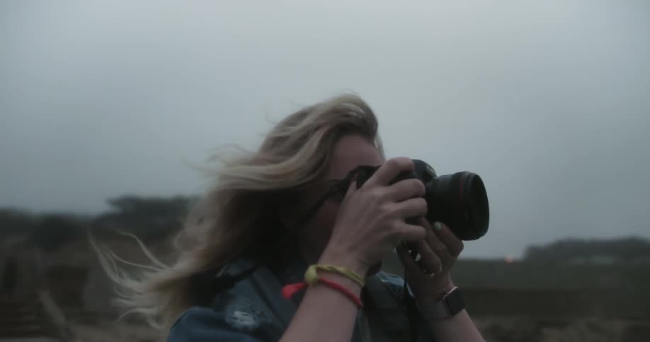A woman taking photographs outside when it is windy