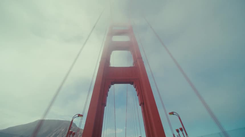 Moving backward on a bridge past mountains in the fog