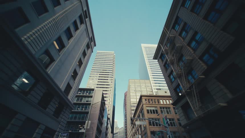 A narrow street framed by tall buildings revealing a glimpse of the sky above and emphasizing the urban density