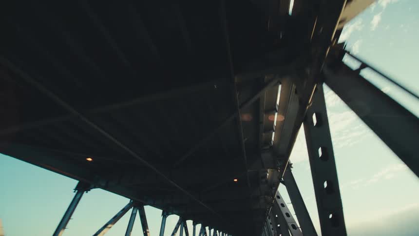 Spaces between the beams of a long covered bridge show the clouds in the sky