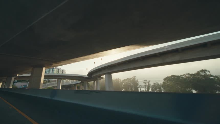 The camera is moving passed the freeway over passes and is over looking the water and the city in the distant
