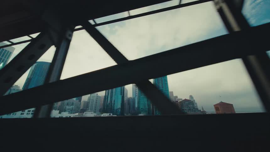 Bridge faces the city skyline under a cloudy sky